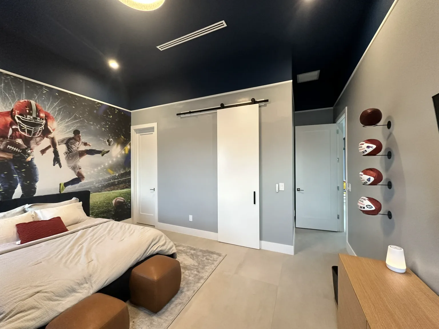 Bedroom with a dark ceiling, wall graphics and sports displays